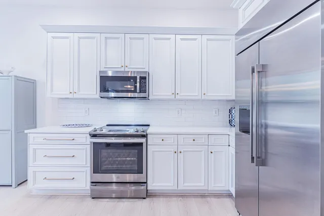 a kitchen with white cabinets and stainless steel appliances