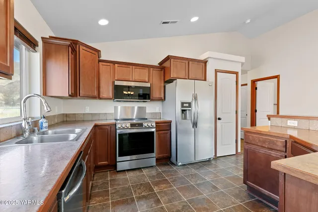 a kitchen with stainless steel appliances granite countertop a refrigerator stove and sink