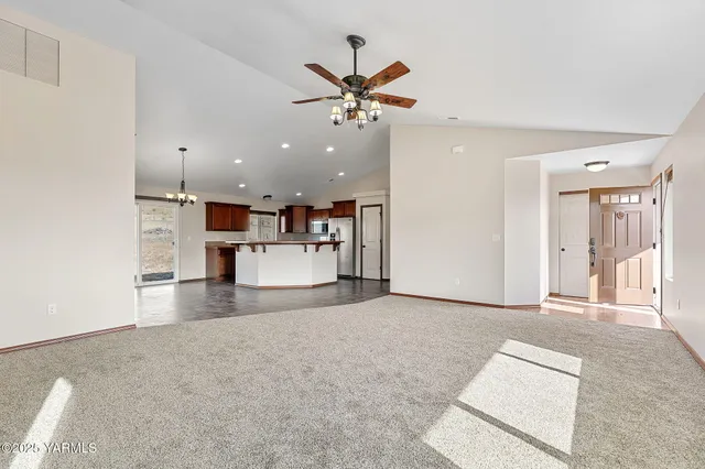 a view of an empty room with kitchen view and a window