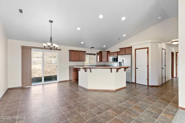 a large kitchen with stainless steel appliances granite countertop a refrigerator a oven a sink and a wooden floors