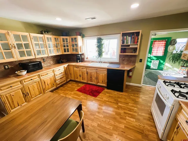 a kitchen with stainless steel appliances kitchen island granite countertop a table chairs in it and wooden floor