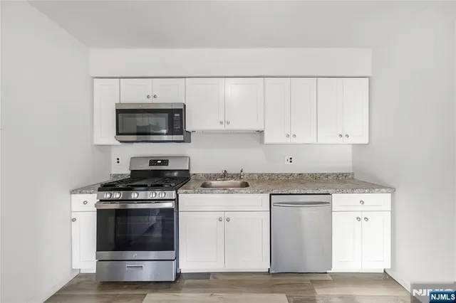 a kitchen with granite countertop a stove top oven and cabinets