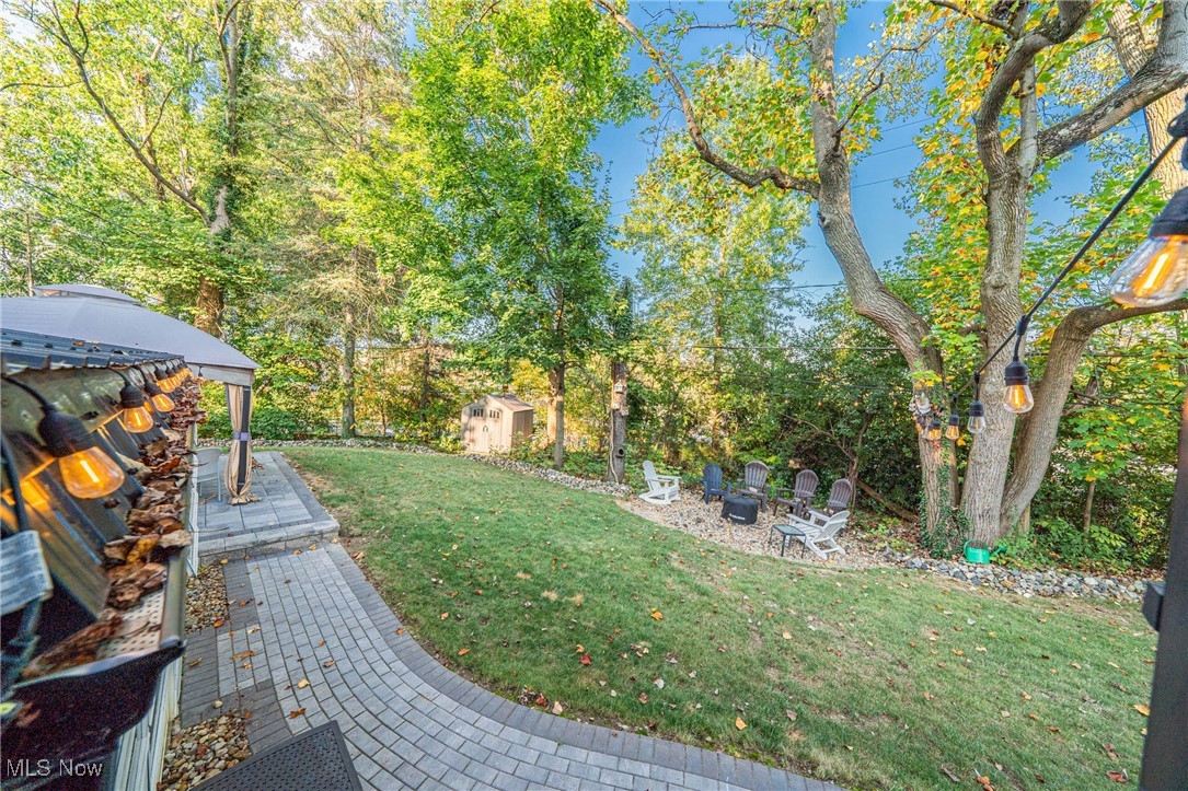595 Moorfield Road Fairlawn, OH 44313 - Photo 49 of 50 View of green lawn featuring a patio area, a storage shed, an outdoor fire pit, and view of scattered trees