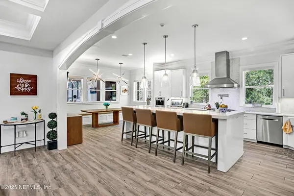 a kitchen with stainless steel appliances granite countertop a table chairs stove a sink dishwasher and cabinets with wooden floor