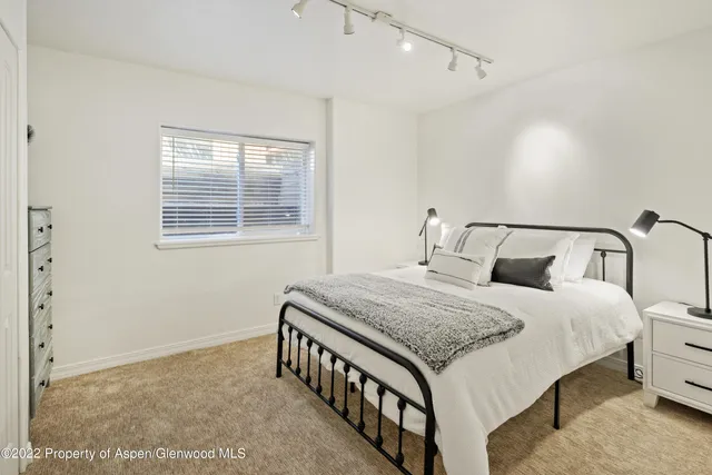 a bedroom with a bed a dresser and window