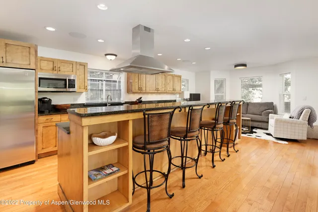 a kitchen with stainless steel appliances kitchen island granite countertop a stove a sink a dining table and chairs