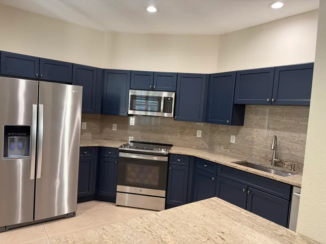 a kitchen with granite countertop a refrigerator and a stove top oven