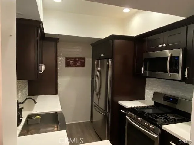 a kitchen with granite countertop a refrigerator and a stove top oven