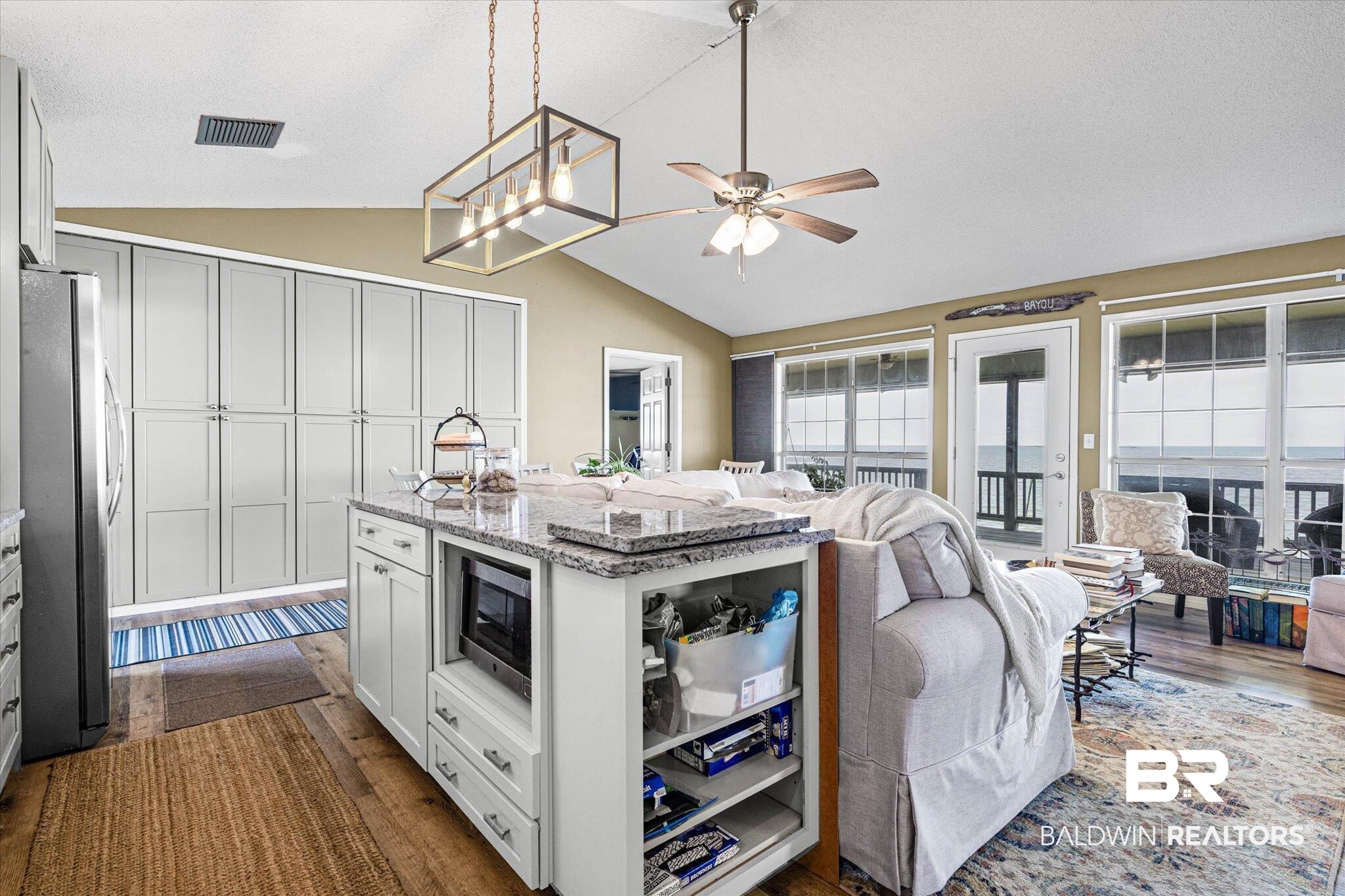9100 Shell Belt Road Coden, AL 36523 - Photo 10 of 38 Open-concept living space with vaulted ceilings featuring a central kitchen island with granite-style countertop, a built-in microwave, and ample storage