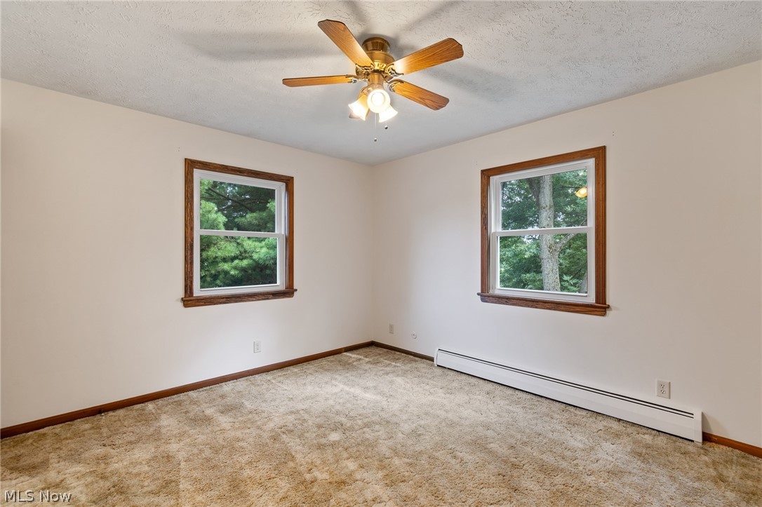 34 Kehner Road Mogadore, OH 44260 - Photo 18 of 40 Neutral wall paint, wood window trim, two windows, ceiling fan, and carpeted flooring