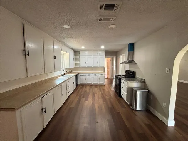 a large kitchen with cabinets wooden floor and stainless steel appliances