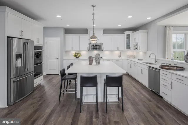 a kitchen with stainless steel appliances a dining table chairs stove refrigerator and microwave