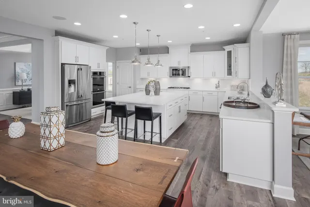 a kitchen with stainless steel appliances granite countertop a sink a stove a refrigerator cabinets and chairs