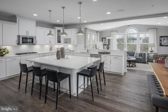 a kitchen with stainless steel appliances a dining table chairs stove and white cabinets