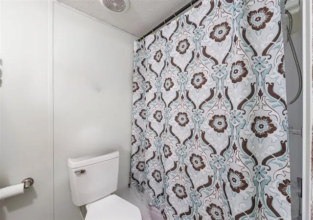 a white toilet sitting next to a shower curtain
