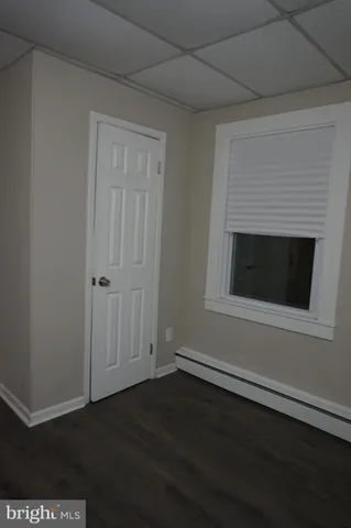 an empty room with wooden floor fireplace and windows