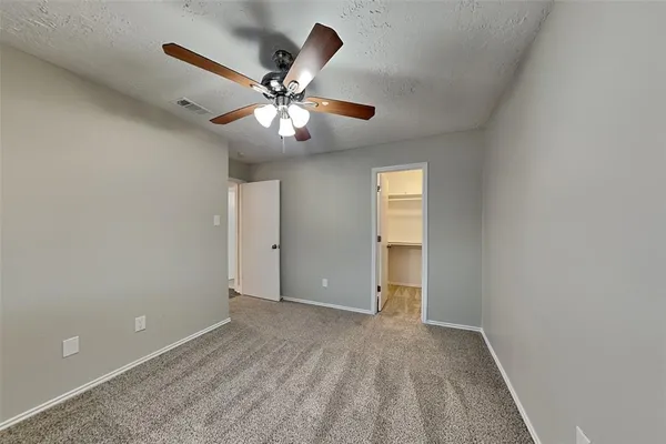 a view of an empty room with chandelier fan