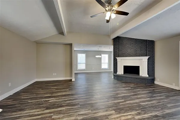 a view of an empty room with wooden floor fireplace and a window