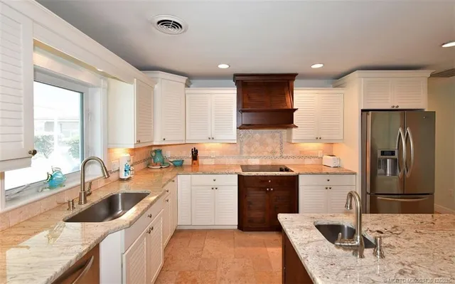 a large white kitchen with stainless steel appliances granite countertop a refrigerator and a stove top oven