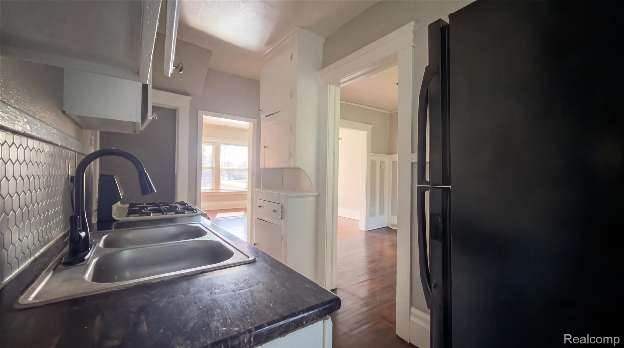 9426 John R Street Detroit, MI 48202 - Photo 8 of 17 Kitchen featuring a double basin stainless steel sink with a matte black gooseneck faucet, dark countertops, and a full-height picket tile backsplash