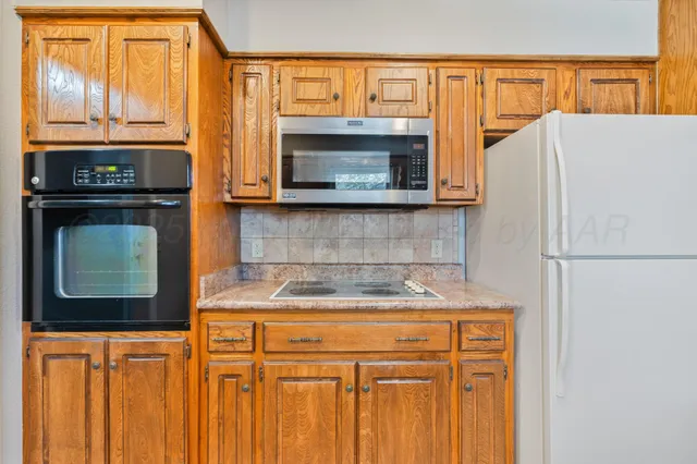 a kitchen with stainless steel appliances granite countertop a refrigerator and a stove top oven
