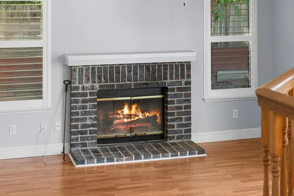 a view of an empty room with wooden floor fireplace and windows