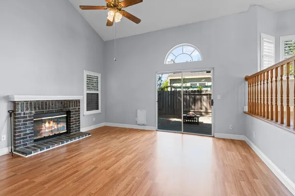 a view of an empty room with wooden floor fireplace and a window