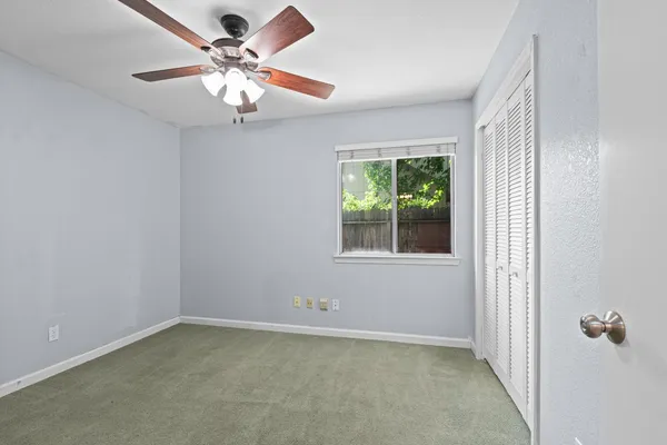 an empty room with a window and a fan
