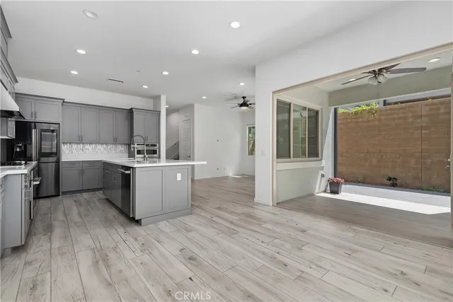 a large white kitchen with stainless steel appliances kitchen island a large counter top and wooden floors