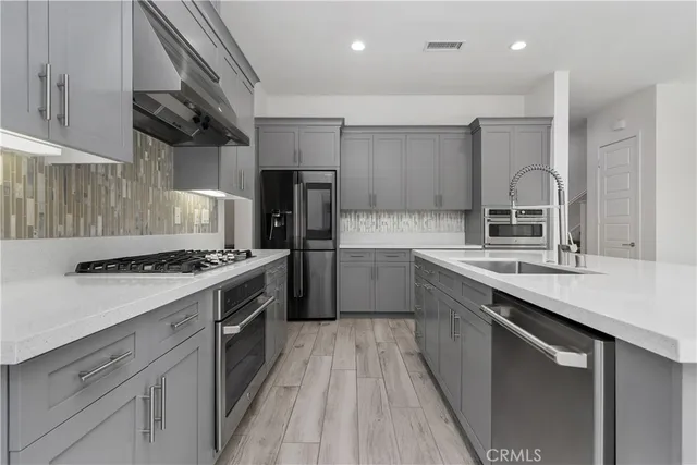 a kitchen with stainless steel appliances a sink dishwasher stove refrigerator and cabinets