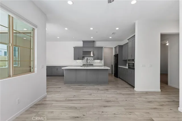 a large white kitchen with kitchen island a sink stainless steel appliances and cabinets