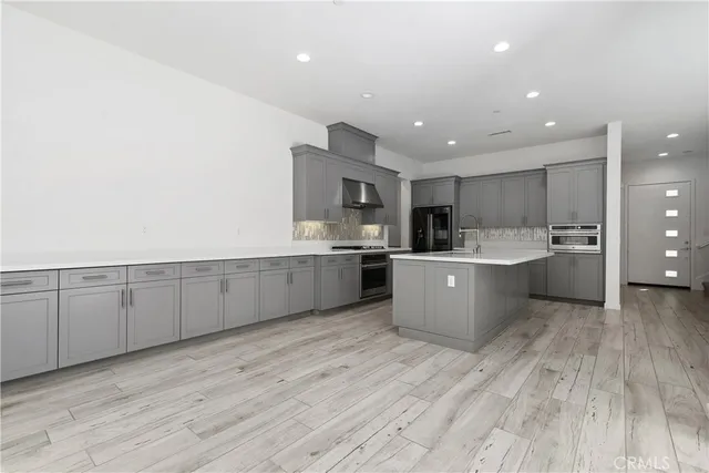 a large kitchen with stainless steel appliances granite countertop a large counter top and a stove with wooden floor