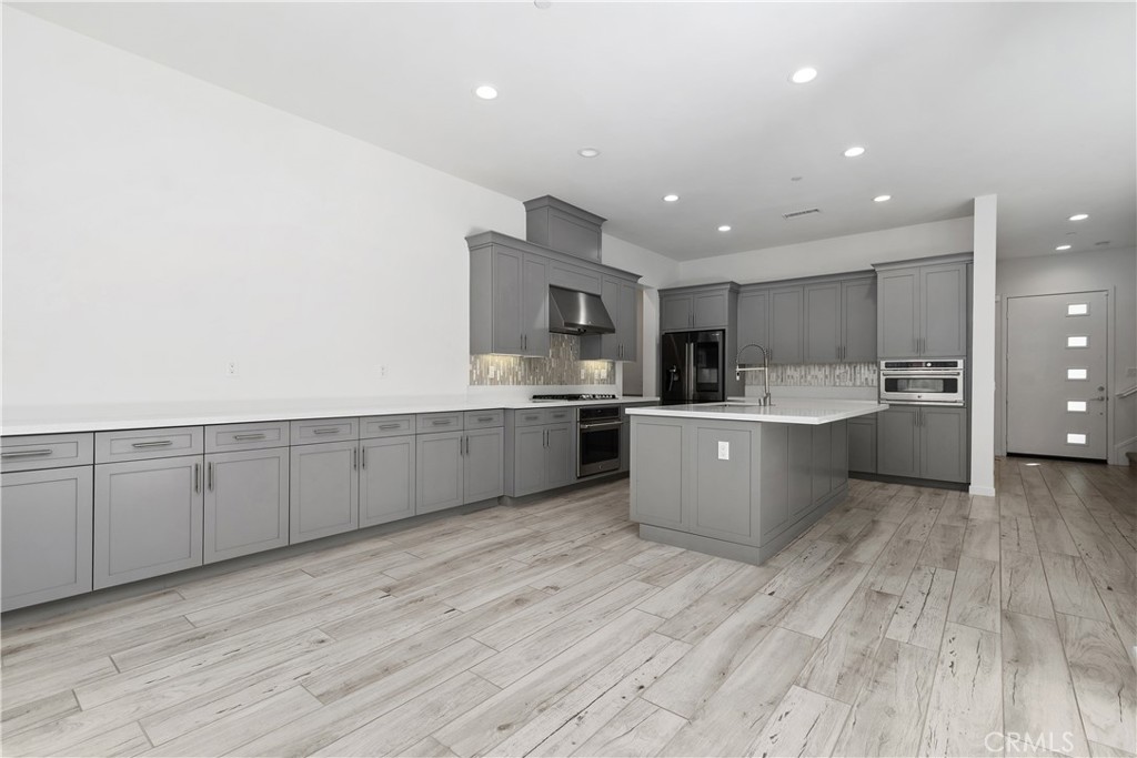 112 Menkar Irvine, CA 92618 - Photo 10 of 54 a large kitchen with stainless steel appliances granite countertop a large counter top and a stove with wooden floor