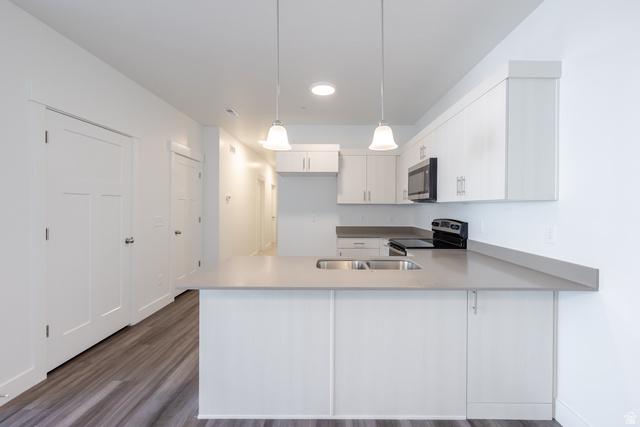 4662 Poplar Way, Unit Q301 Mapleton, UT 84664 - Photo 4 of 18 Kitchen with a peninsula, stainless steel appliances, dark wood finished floors, pendant lighting, and light countertops