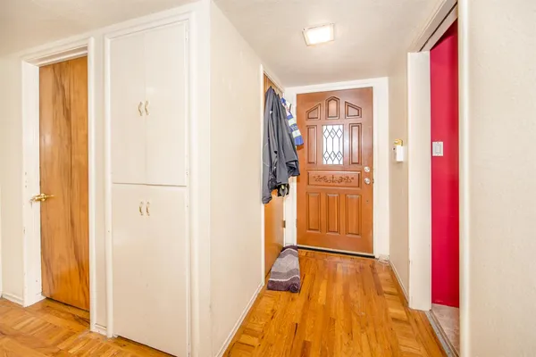 a view of a hallway with wooden floor and cabinet