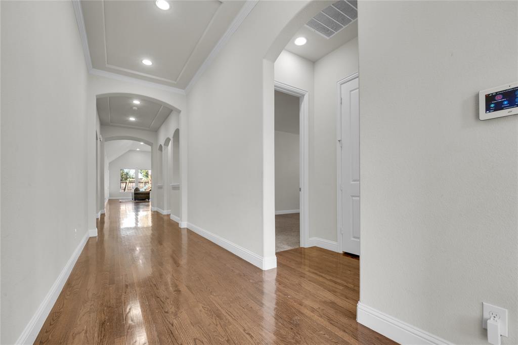 1011 Prairie Ridge Lane Arlington, TX 76005 - Photo 17 of 32 Long hallway featuring wood-finish flooring, recessed lighting, arched doorways, and tray ceilings