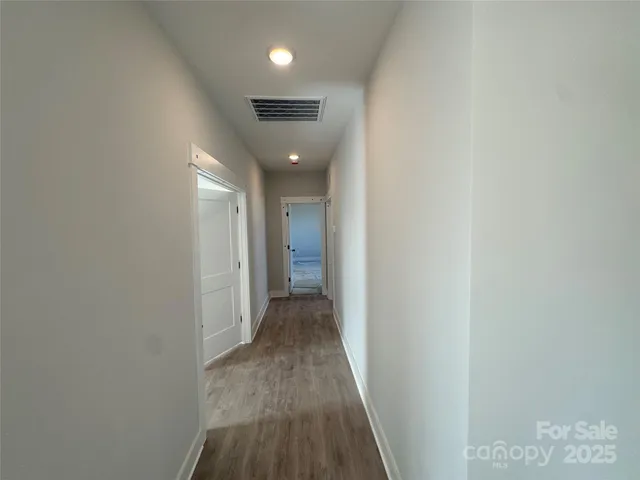 a view of a hallway with wooden floor and closet