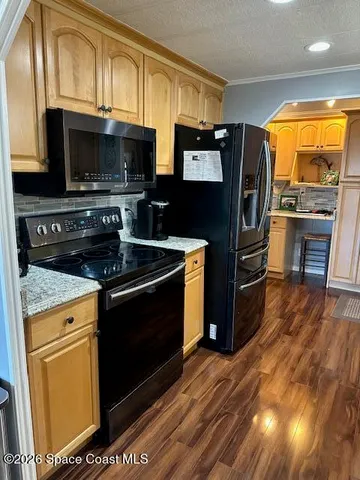 a kitchen with stainless steel appliances a stove a microwave and a hard wood floor