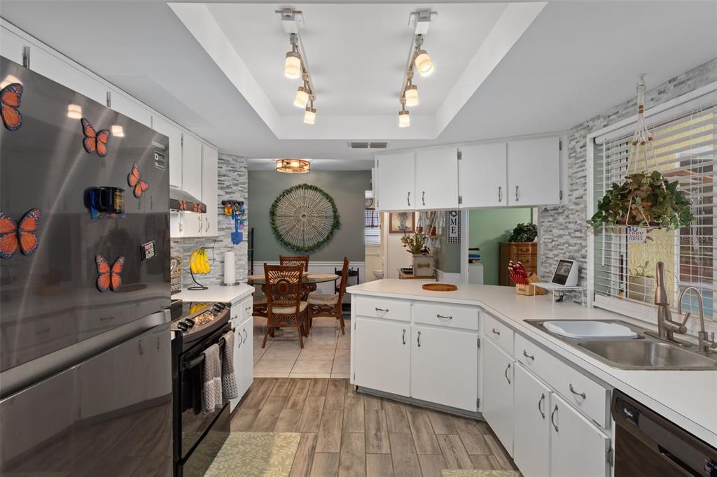 6101 County Line Road Spring Hill, FL 34606 - Photo 14 of 40 a kitchen with a sink dishwasher a stove and a dining table with wooden floor