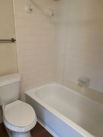 a white toilet sitting next to a bath tub