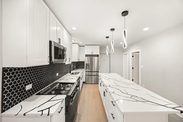 a kitchen with stainless steel appliances kitchen island granite countertop a stove and white cabinets