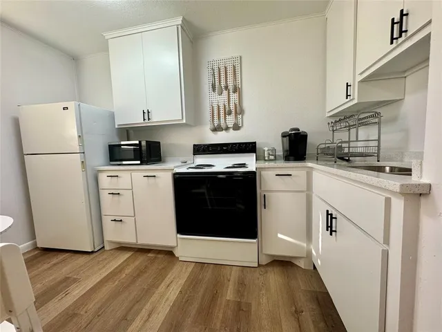 a kitchen with cabinets appliances and wooden floor