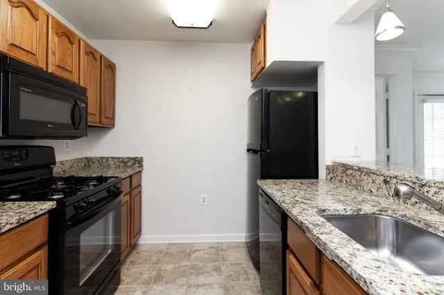 a kitchen with granite countertop a sink stove and refrigerator