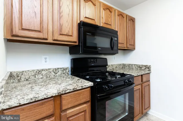 a kitchen with granite countertop a stove top oven microwave and cabinets