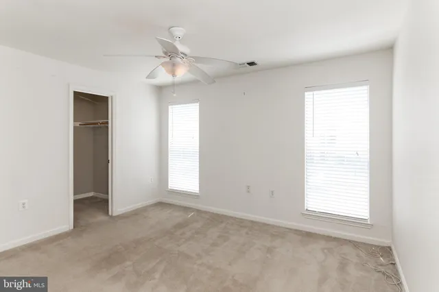 an empty room with windows and fan