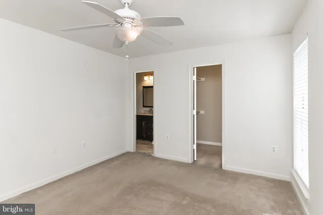an empty room with closet and a ceiling fan