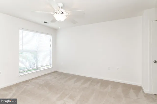 an empty room with windows and ceiling fan
