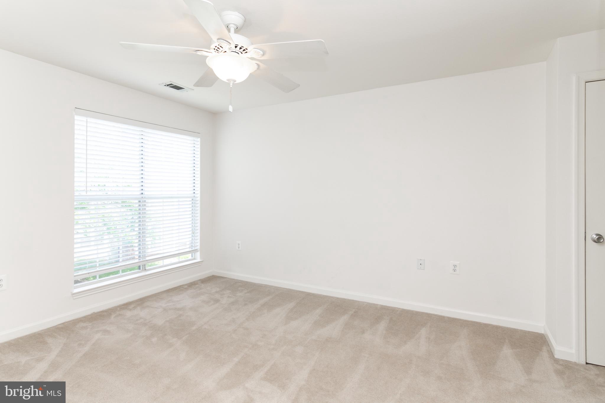 20958 Timber Ridge Terrace, Unit 201 Ashburn, VA 20147 - Photo 8 of 25 an empty room with windows and ceiling fan