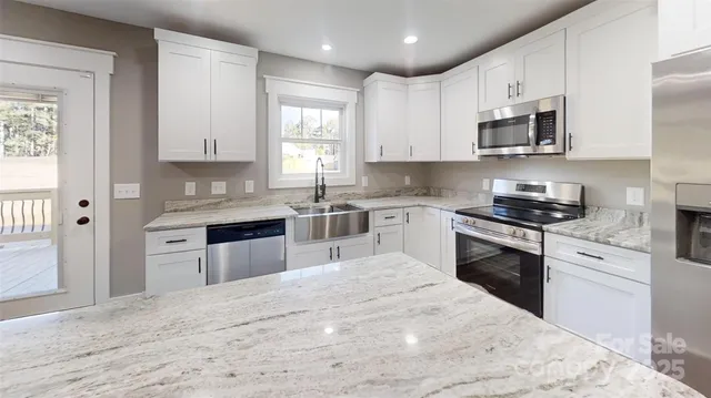 a kitchen with stainless steel appliances granite countertop a stove top oven a sink dishwasher and a refrigerator with wooden floor