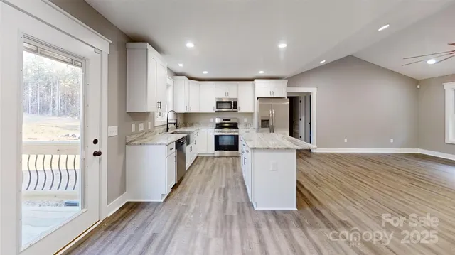 a kitchen with kitchen island wooden floors appliances and cabinets